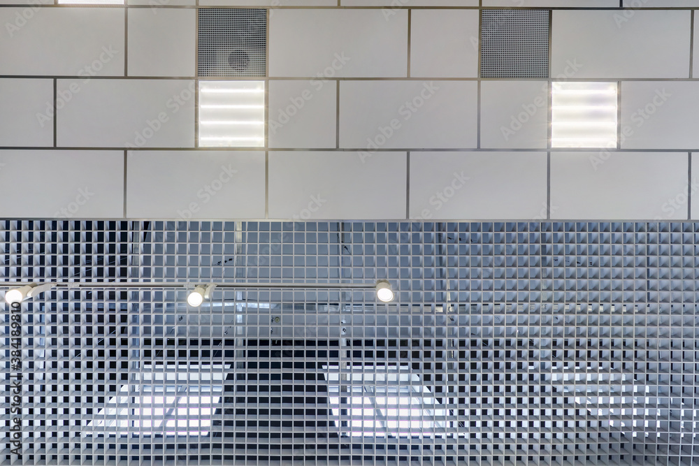 Obraz premium cassette suspended ceiling with square halogen spots lamps and drywall construction in empty room in apartment or house. Stretch ceiling white and complex shape. Looking up view