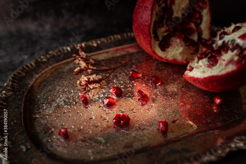 red pomegranate seeds with water drops on a beautiful vintage tray