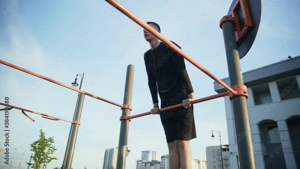 Side view of young muscular man doing Muscle Up exercise on bar outdoors Side view of young muscular man doing Muscle Up exercise on bar outdoors
