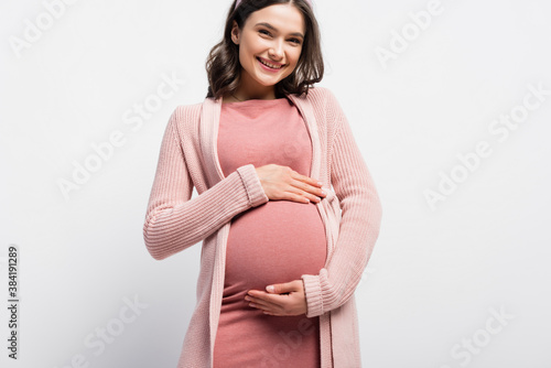 Foto joyful pregnant woman touching belly on white