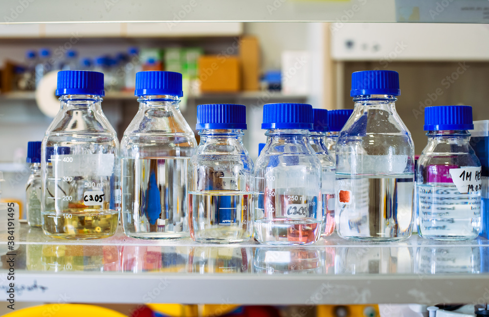 Stock solutions for biochemistry experiments, bottles with blue cap are on a shelf, blurry background Stock solutions for biochemistry experiments, bottles with blue cap are on a shelf, blurry background