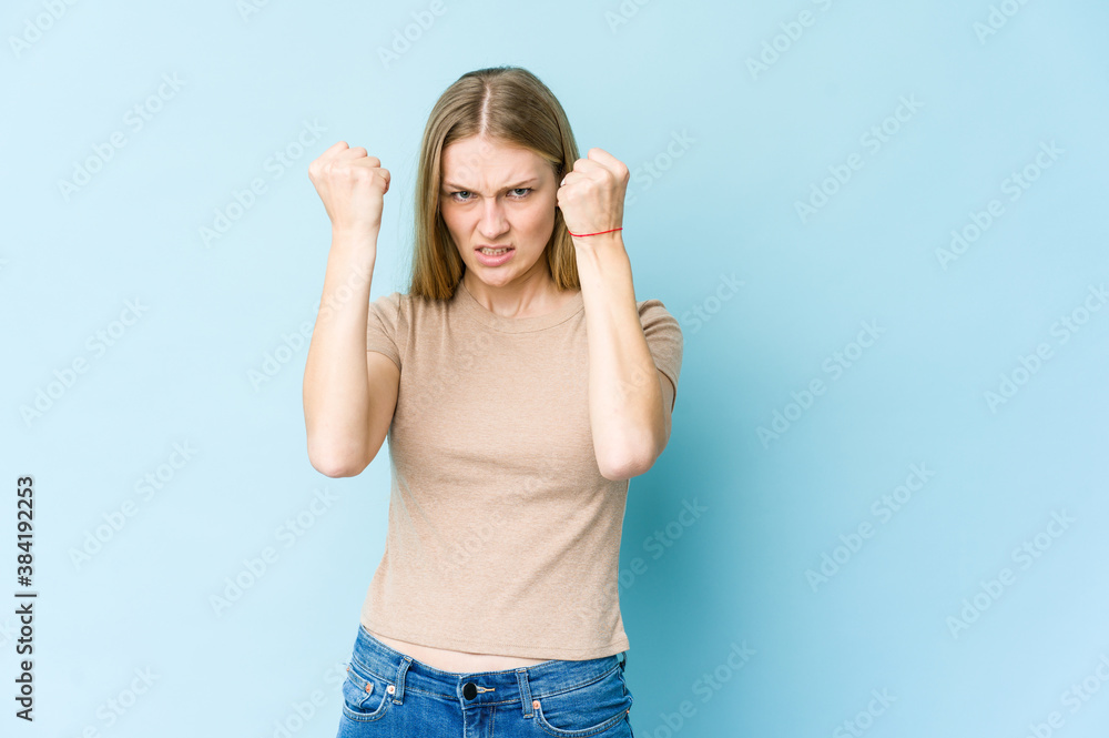 Young blonde woman isolated on blue background upset screaming with tense hands. Young blonde woman isolated on blue background upset screaming with tense hands.