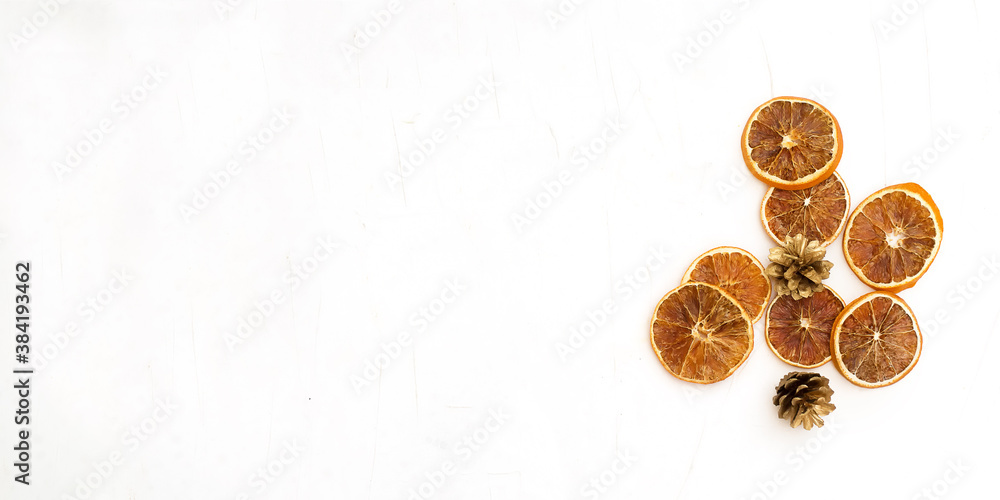 Christmas composition. Dried sliced oranges and golden cones on a white background.