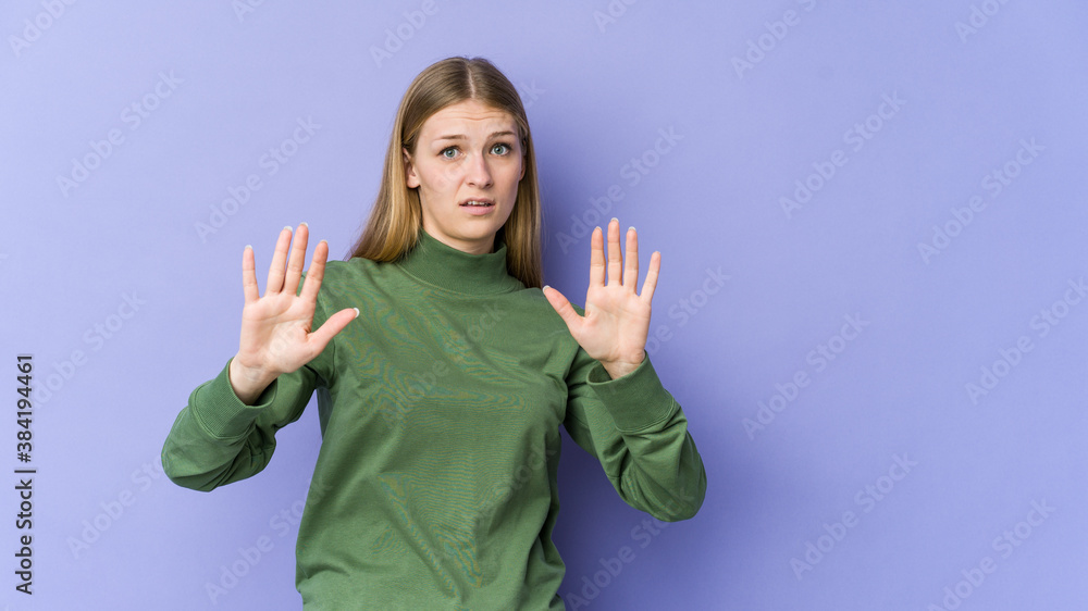 Young blonde woman isolated on purple background being shocked due to an imminent danger Young blonde woman isolated on purple background being shocked due to an imminent danger