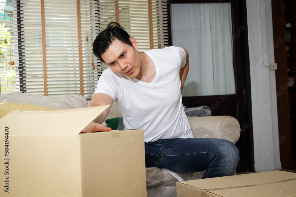 An Asian man has pain after lifting heavy objects to move into a new home. During COVID19 An Asian man has pain after lifting heavy objects to move into a new home. During COVID19