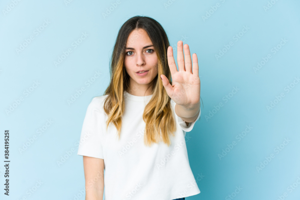 Young caucasian woman isolated on blue background standing with outstretched hand showing stop sign, preventing you. Young caucasian woman isolated on blue background standing with outstretched hand showing stop sign, preventing you.