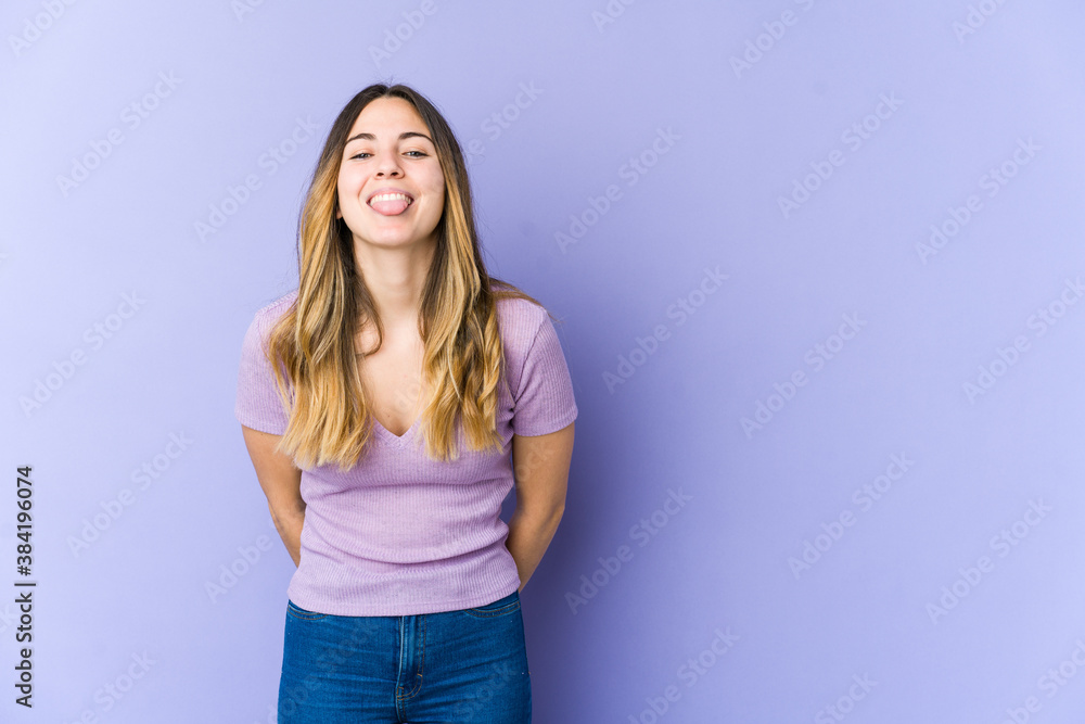 Young caucasian woman isolated on purple background funny and friendly sticking out tongue. Young caucasian woman isolated on purple background funny and friendly sticking out tongue.