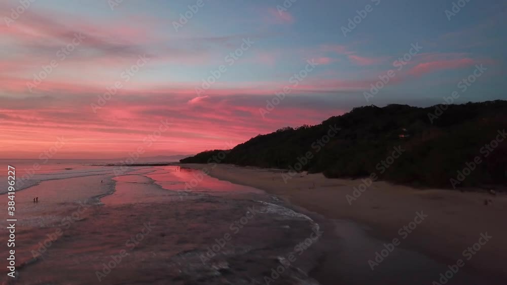 Amazing Sunset Sky In Fiery Red Color By The Beach In Santa Teresa, Costa Rica With Lush Tropical Island Coast In Silhouette - ascending drone shot