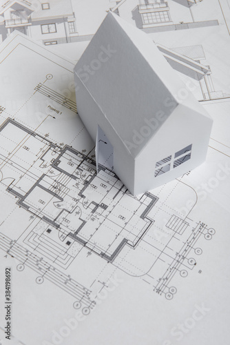 White family paper house, house projects plan and blueprints on yellow background paper. Minimalistic and simple concept, style. Vertical orientation