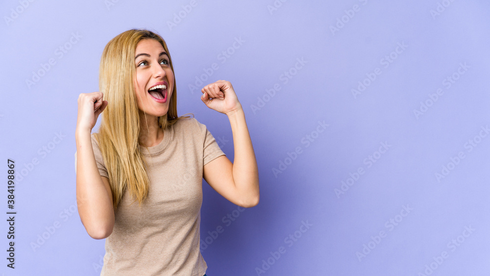 Young blonde caucasian woman raising fist after a victory, winner concept. Young blonde caucasian woman raising fist after a victory, winner concept.