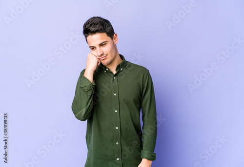 Young caucasian man isolated on purple background who feels sad and pensive, looking at copy space.