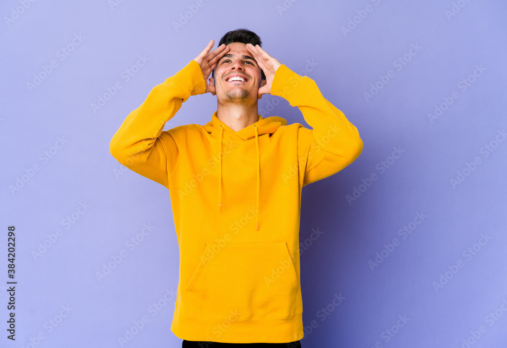 Young caucasian man isolated on purple background laughs joyfully keeping hands on head. Happiness concept. Young caucasian man isolated on purple background laughs joyfully keeping hands on head. Happiness concept.