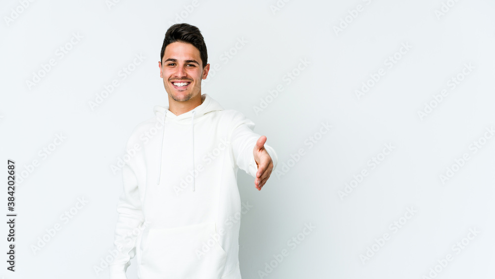 Young caucasian man isolated on white background stretching hand at camera in greeting gesture. Young caucasian man isolated on white background stretching hand at camera in greeting gesture.