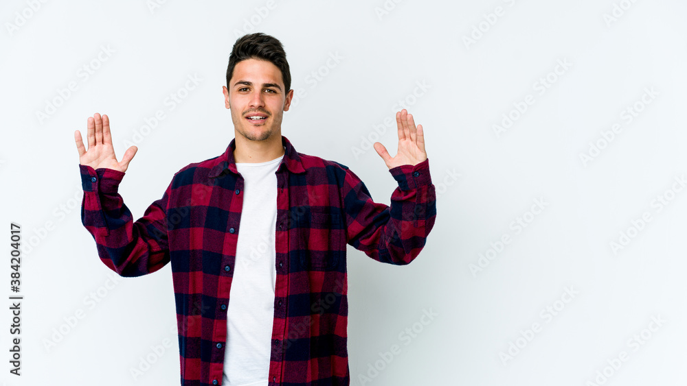 Naklejka premium Young caucasian man isolated on white background holding something little with forefingers, smiling and confident.