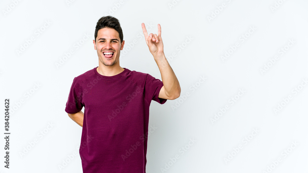 Young caucasian man isolated on white background showing rock gesture with fingers Young caucasian man isolated on white background showing rock gesture with fingers