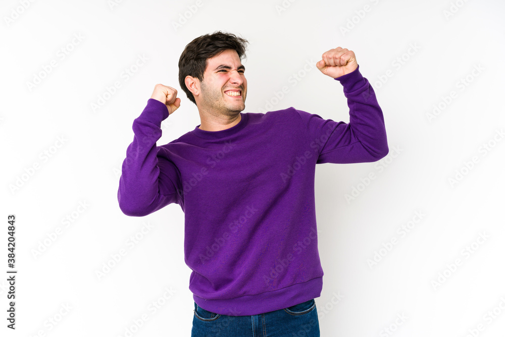 Young man isolated on white background raising fist after a victory, winner concept. Young man isolated on white background raising fist after a victory, winner concept.