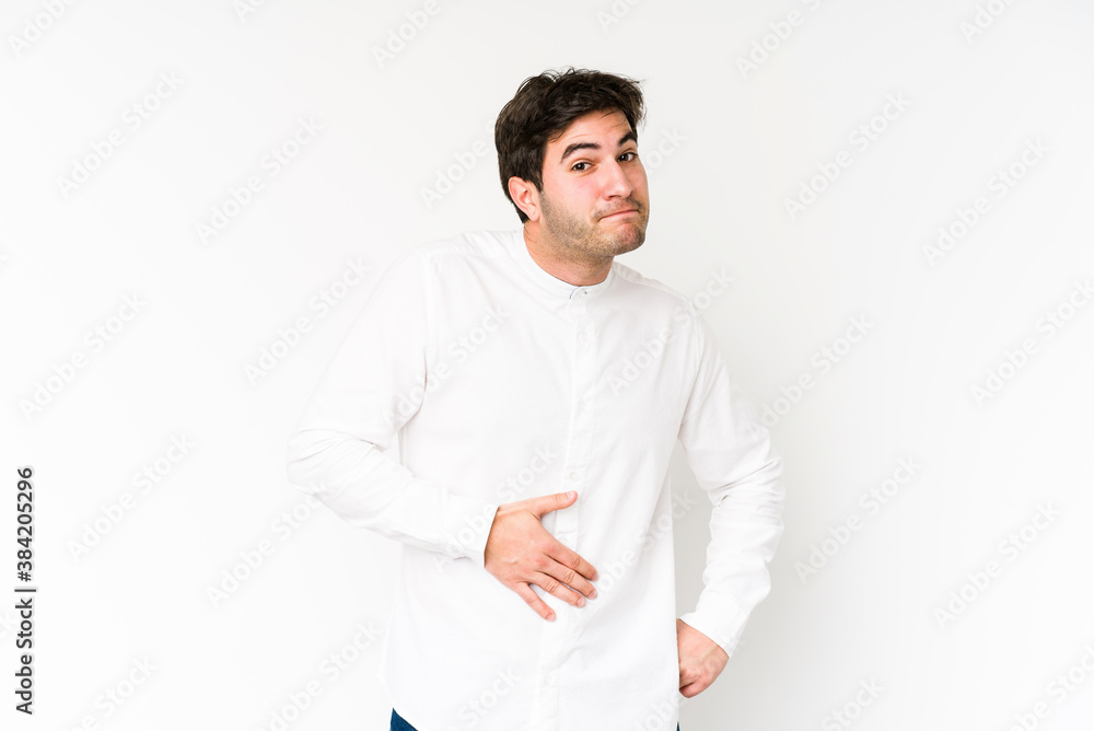 Young man isolated on white background touches tummy, smiles gently, eating and satisfaction concept. Young man isolated on white background touches tummy, smiles gently, eating and satisfaction concept.