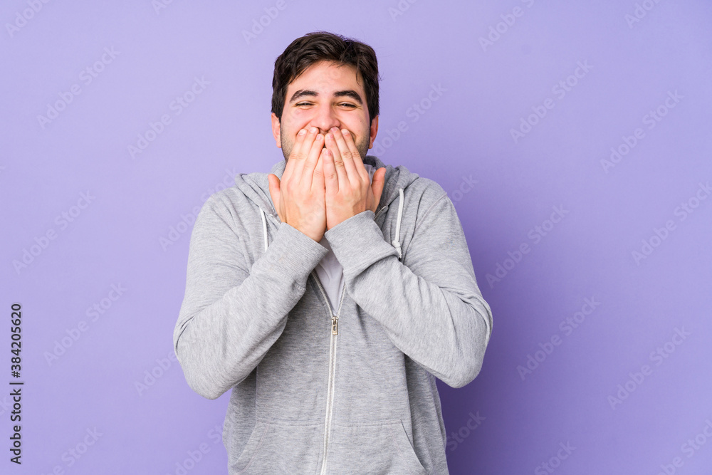 Young man isolated on purple background laughing about something, covering mouth with hands. Young man isolated on purple background laughing about something, covering mouth with hands.