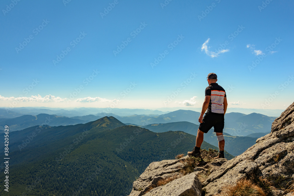 Fototapeta premium A tourist on top of a large stone block, the top of Smotrych mountain, one of the rocky peaks of the Ukrainian Carpathians.