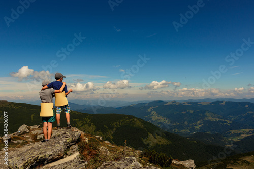 Two small children, brothers boys standing on one rocky peak, a mountain of Carpathian mountains, happy children, children on a hike.
