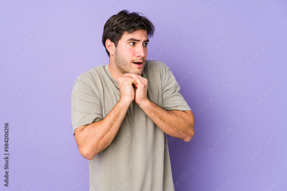 Young man isolated on purple background praying for luck, amazed and opening mouth looking to front. Young man isolated on purple background praying for luck, amazed and opening mouth looking to front.