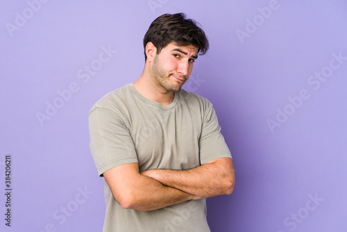Young man isolated on purple background unhappy looking in camera with sarcastic expression.