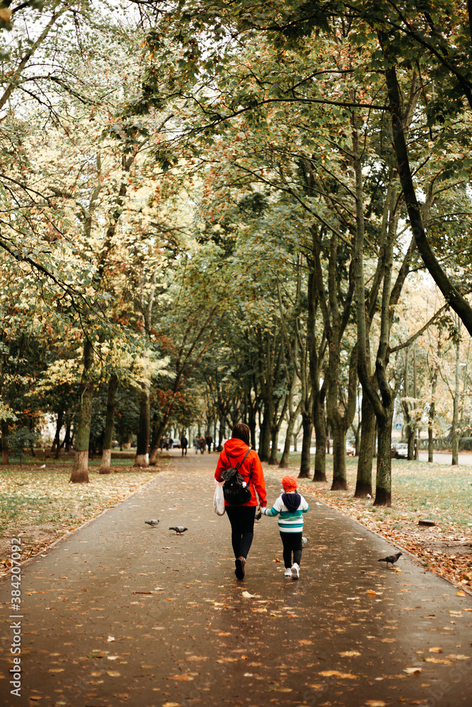 Mom and daughter are walking in the forest. Autumn, it's raining outside
