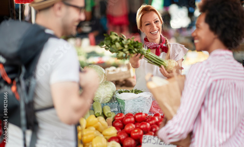 Seller woman offers fresh and organic vegetables at the green market or farmers market stall. Young buyers choose and buy products for healthy food in grocery. All for diet healthy eating, lifestyle.