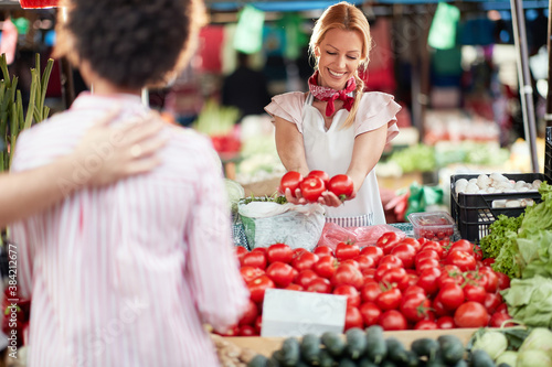 Seller woman offers fresh and organic vegetables at the green market or farmers market stall. Young buyers choose and buy products for healthy food in grocery. All for diet healthy eating, lifestyle.