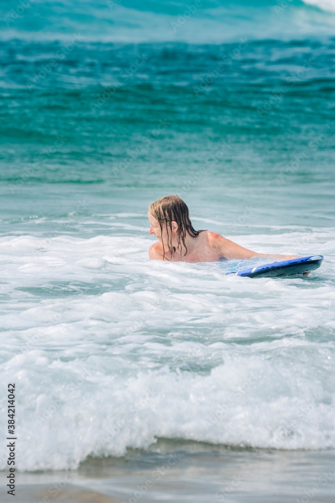 Woman with surfboard in waves of Atlantic Ocean
