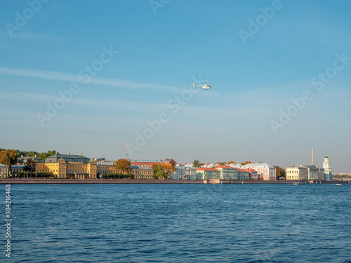 White helicopter flies over the Neva river in Saint Petersburg.
