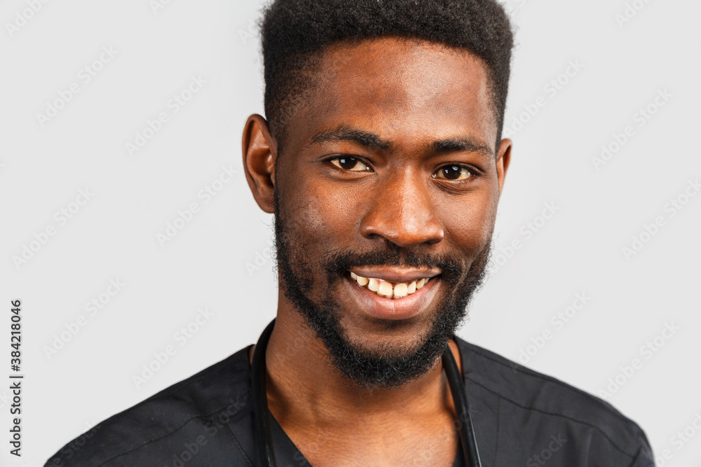 close-up portrait of a happy African doctor in black medical uniform on a gray background. close-up portrait of a happy African doctor in black medical uniform on a gray background.