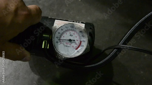 someone checks the pressure on a portable car tire inflator