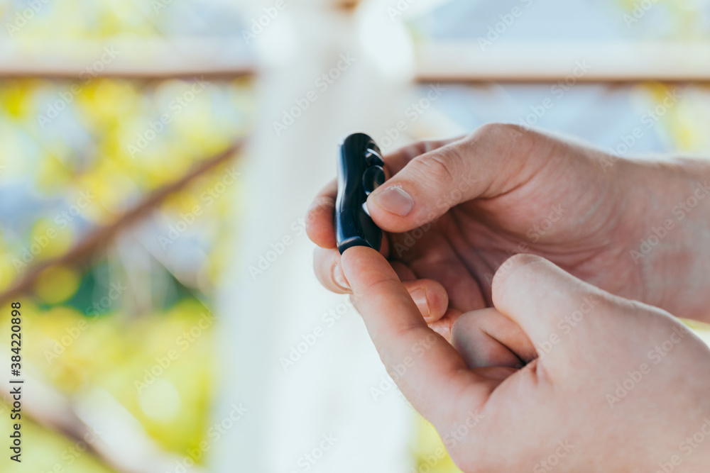 Fototapeta premium medicine, diabetes, medicine and people concept - close up of a man with a blood glucose meter and a test strip checking blood sugar at home. Diabetes Day, November 14
