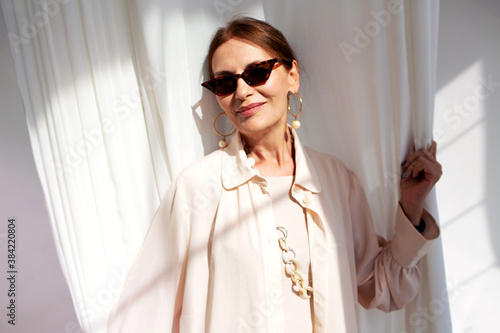 Canvas Print Headshot of beautiful stylish elderly mature woman looking at camera and smiling while standing at  white background