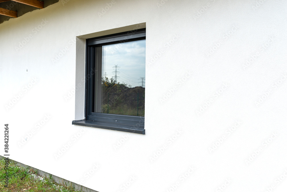 A newly applied layer of white silicone plaster on the wall of the house, visible window in anthracite. A newly applied layer of white silicone plaster on the wall of the house, visible window in anthracite.