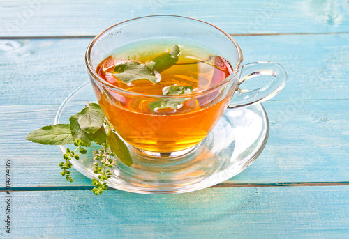 Tulsi tea served in a glass cup with tulsi or holi basil leaves. Tulsi has many benefits for body and brain.