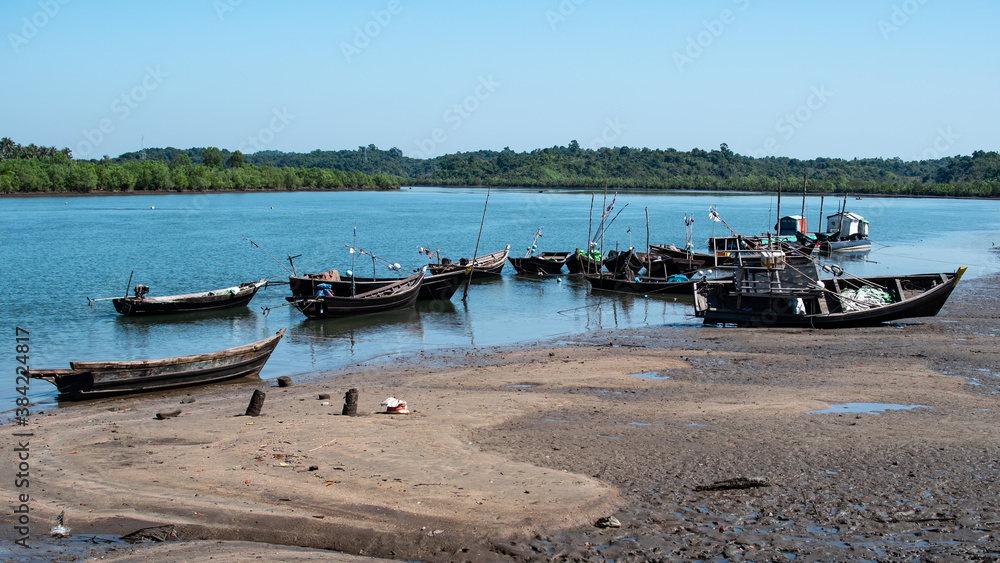 Wooden fishing boats by the river during low tide, Chaung Thar, Myanmar Wooden fishing boats by the river during low tide, Chaung Thar, Myanmar