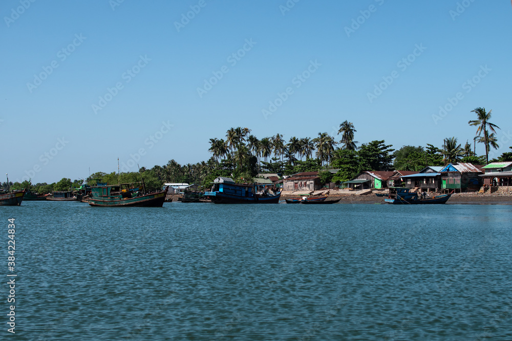 Several traditional wooden boats and houses on the shore of Chaung Thar, Myanmar Several traditional wooden boats and houses on the shore of Chaung Thar, Myanmar
