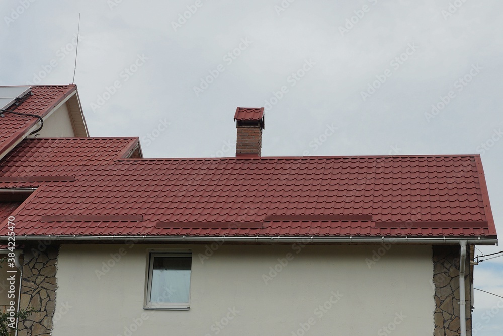 attic of a private house with a window on a brown wall under a red tiled roof against a gray sky attic of a private house with a window on a brown wall under a red tiled roof against a gray sky