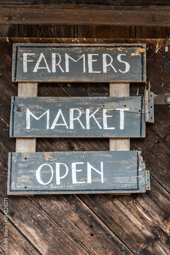 rustic wooden sign hanging on a wall says farmers market open