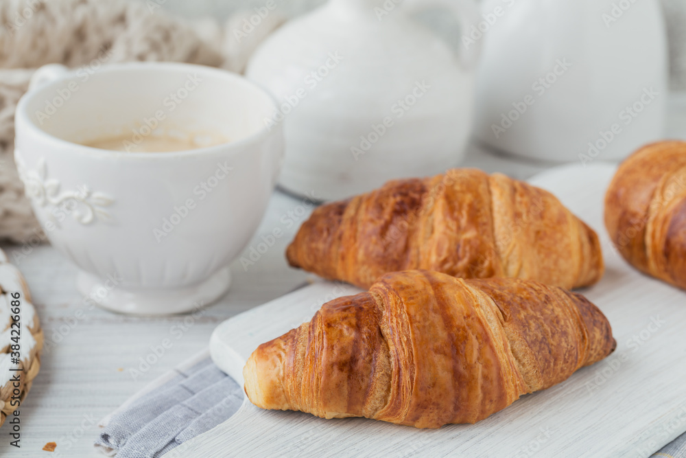 Delicious breakfast with fresh croissants and cup of coffee on a white wooden background. Delicious Baking