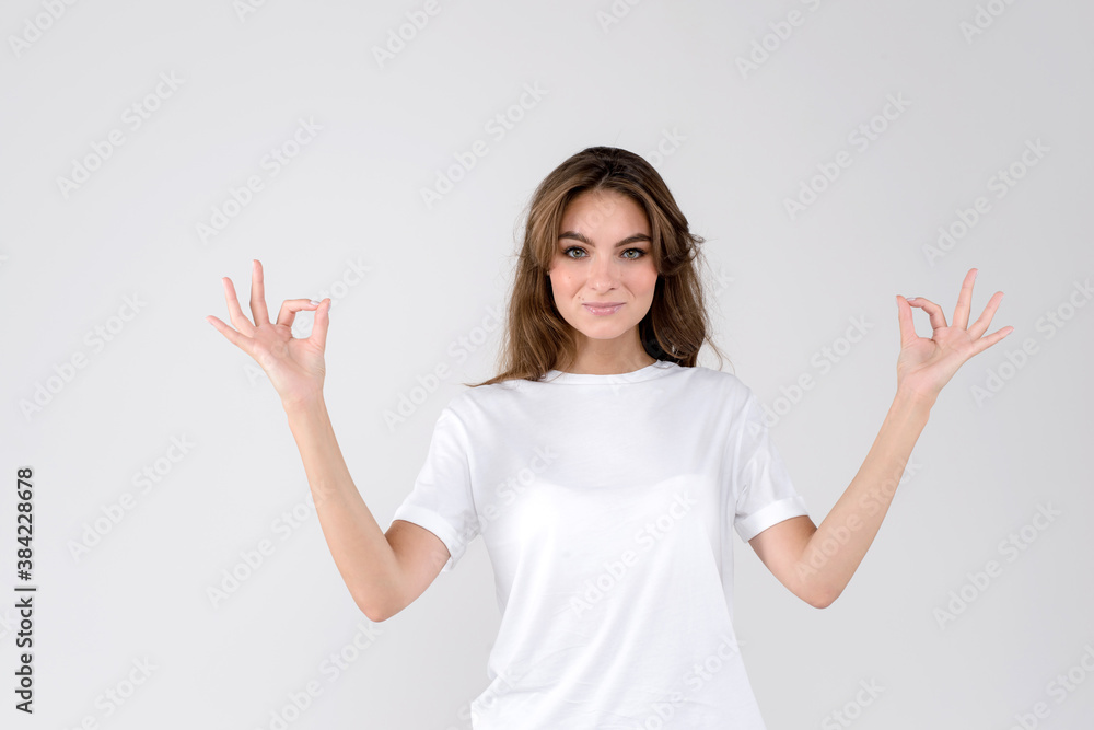 Beautiful young woman showing ok gesture with two hands isolated on white background Beautiful young woman showing ok gesture with two hands isolated on white background