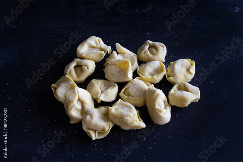 Fresh Ravioli on floury dark background. Italian homemade healthy food concept.Process of making italian ravioli.