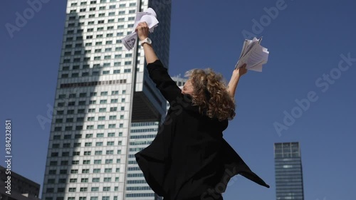 Young career woman extremally excited for her professional success jumps holding papers in hands  photo