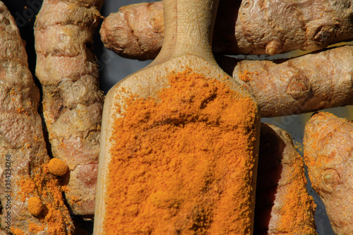 Turmeric powder (Kurkuma) in a wooden spoon and roots photo