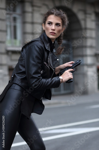 A girl on a city street with a gun in her hands