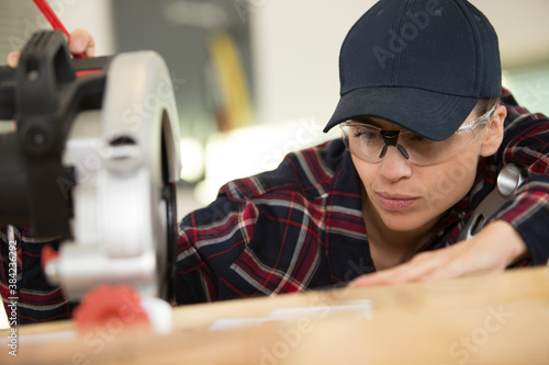 young woman using modern electric saw in the workshop