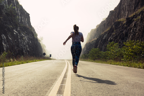 Young fitness woman running on the rout.  Mountain landscape in foggy day.  Concept of outdoor sport. photo