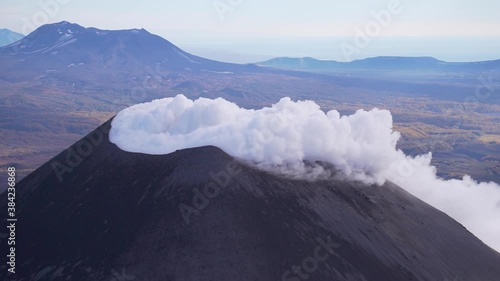 The crater of Karymsky volcano on the Kamchatka Peninsula thick white smoke photo